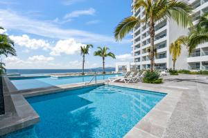 a swimming pool with palm trees and a building at Studio Ala Kai in Puerto Vallarta
