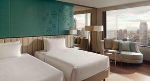 a hotel room with two beds and a chair at InterContinental Bangkok by IHG in Bangkok