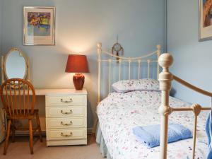 a bedroom with a bed and a chair and a dresser at The Cottage in Blakeney +11 photos