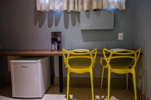 two yellow chairs sitting next to a table with a computer at Ouro Motel in Sepetiba