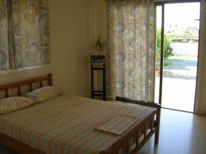 een slaapkamer met een bed en een glazen schuifdeur bij Marios Apartments in Perivolia