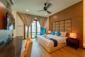 a bedroom with a large bed and a flat screen tv at Telaga Village Resort in Pantai Cenang
