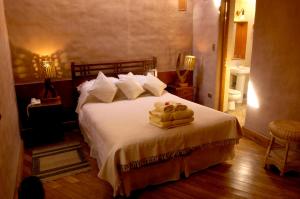 1 dormitorio con 1 cama con 2 toallas en Hotel Kimal, en San Pedro de Atacama