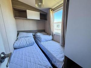 two beds in a small room with a window at Spacious 8 Berth Caravan At Dovercourt Holiday Park, Essex Ref 44202K in Great Oakley +13 photos
