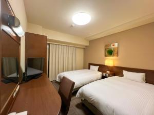 a hotel room with two beds and a flat screen tv at Hotel Route-Inn Hirosaki Joto in Hirosaki