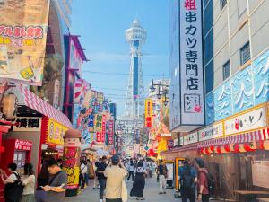una multitud de personas caminando por una concurrida calle de la ciudad en バンデホテル in なんば, en Osaka