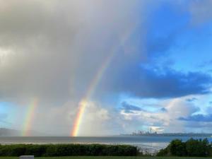 ein Regenbogen am Himmel über dem Wasser in der Unterkunft Auckland Luxury Seafront House in Auckland + 53 Fotos