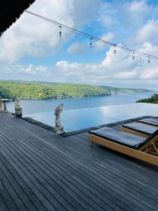 a deck with a view of a body of water at Ceningan Cliff Cottages in Nusa Lembongan +24 photos