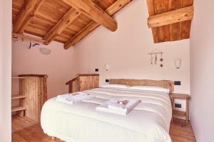 um quarto com uma grande cama branca e tectos em madeira em Locanda Del Silenzio Residence em Macra