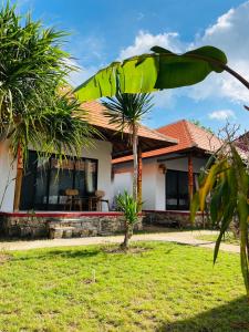 a house with a palm tree in front of it at Ceningan Cliff Cottages in Nusa Lembongan