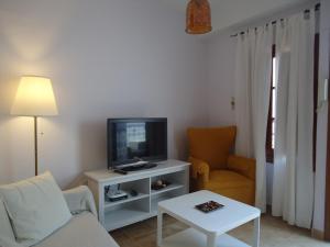 un soggiorno con una TV, un divano e un tavolo di Apartamentos Acevedo Centro a Ronda