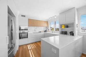 a white kitchen with white cabinets and a refrigerator at Stylish 4-Bed Townhouse with Panoramic Ocean Views in Brisbane