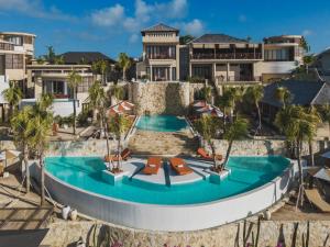 einen Luftblick auf einen Resortpool mit Stühlen und Sonnenschirmen in der Unterkunft Seascape Resort & Spa Uluwatu by Ini Vie Hospitality in Uluwatu