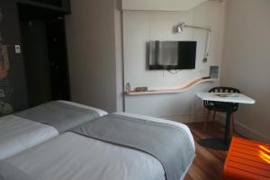 a bedroom with two beds and a tv on the wall at ibis Styles Deauville Centre in Deauville
