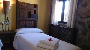 1 dormitorio con 1 cama con toallas y ventana en Valdolázaro, en Los Navalucillos