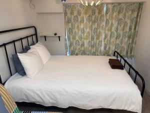 東京にある5minutes from Shinjuku Shin-Okubo Station-k203の白いシーツと窓のあるベッドのある寝室