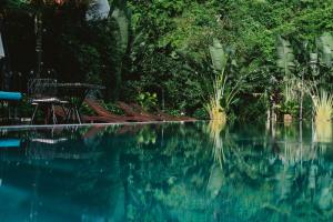 a swimming pool with blue water and trees at Lalita Tam Coc Resort & Spa in Ninh Binh