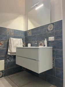 baño con lavabo blanco y azulejos azules en Villa Harmony Retreat, en Budoni