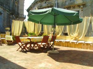 a table and chairs with a green umbrella at Aci e Galatea in Acireale