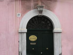 a green door in a pink building with a sign above it at Aci e Galatea in Acireale