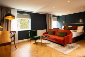 a living room with a bed and a red couch at Rob Roy - Self Check-In Boutique Accommodation in Berwick-Upon-Tweed