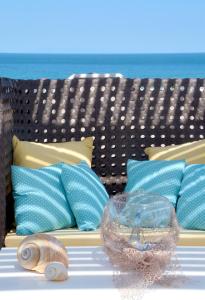 Una cama con almohadas azules y un tazón de cristal. en Rodolithos Beach Studios, en Stavros