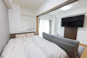 山形市Tomattoco KASUMI的一间卧室，里面有一张床和一台平板电视