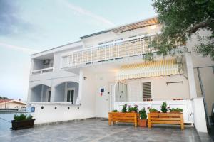 a white house with two benches in front of it at Studios Ruža in Baška Voda