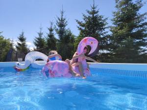 three children riding on inflatables in a swimming pool at Domki letniskowe Wega - basen ogrodowy plac zabaw parking grill wifi in Sianozety