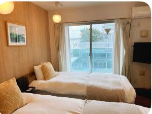 una camera d'albergo con due letti e una finestra di 301 湘南 鵠沼海岸 サーフィンに最適なビーチ近くの独立型アパート a Fujisawa