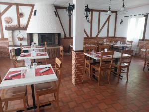 a restaurant with tables and chairs and a fireplace at Logis Auberge De La Plaine in La Rothière