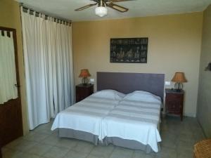 TemisasにあるCasa Vista Palmeralのベッドルーム1室(白いベッド1台、ナイトスタンド2つ、ランプ2つ付)