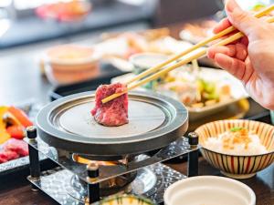 a person eating food on a plate with chopsticks at Kirishima Momijidani Seiryuso - Vacation STAY 63072v in Kirishima