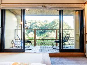 a room with a view of a deck with chairs at Kirishima Momijidani Seiryuso - Vacation STAY 63072v in Kirishima