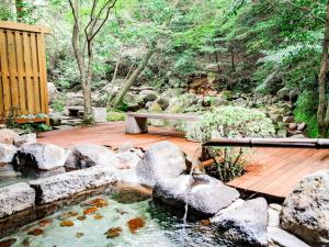 a pond with rocks and a bench on a wooden deck at Kirishima Momijidani Seiryuso - Vacation STAY 63072v in Kirishima