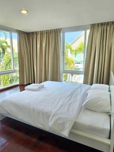 a bedroom with a large white bed with windows at LELAWADEE Villa Cha -Am 