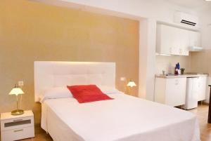 um quarto com uma cama branca e uma almofada vermelha em Marblau Mallorca em Cala Figuera