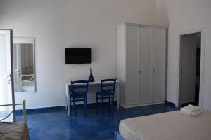 um quarto com uma mesa e cadeiras e uma televisão em La Casa di Cirro em Procida