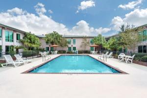 Una piscina en un patio con sillas y un edificio. en Ramada by Wyndham Luling, en Luling