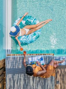 two girls are swimming in a swimming pool at Petra Nera Skiathos, Philian Hotels & Resorts in Agia Paraskevi