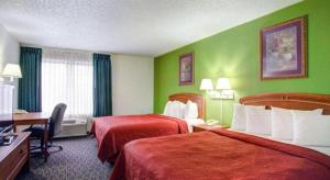 a hotel room with two beds and green walls at Quality Inn & Suites Airport in Austin