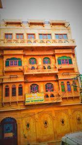 斋沙默尔Hotel Shahiraj Jaisalmer的一座高大的建筑,上面有窗户和标志