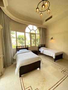 Cette chambre comprend 2 lits dans une chambre dotée de fenêtres et d'un lustre. dans l'établissement El Safwa Resort New Cairo, au Caire