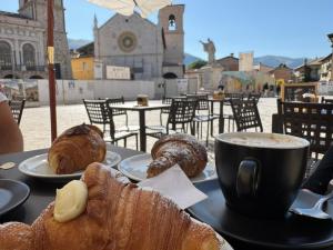 a table with a plate of pastries and a cup of coffee at Affittacamere Il Cuore Verde in Norcia