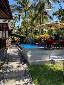 a swimming pool with two chairs and an umbrella at Villa Ganesha Penuktukan in Tejakula