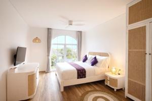 a white bedroom with a bed and a window at 4 Bedroom Ami Cemagi Beach Villa in Cemagi