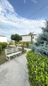 a white bench sitting in a park with bushes at Complex Minerva in Costinesti
