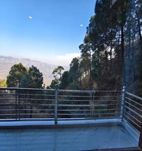 a balcony with a fence and mountains in the background at Claremont Homestay By StayApart in Kasauli