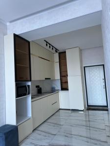 a kitchen with white cabinets and a large window at comfortable 1 bedroom apartment near centre of the city in Dushanbe