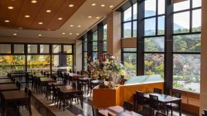 a dining room with tables and chairs and windows at Motosu Phoenix Hotel in Fujikawaguchiko